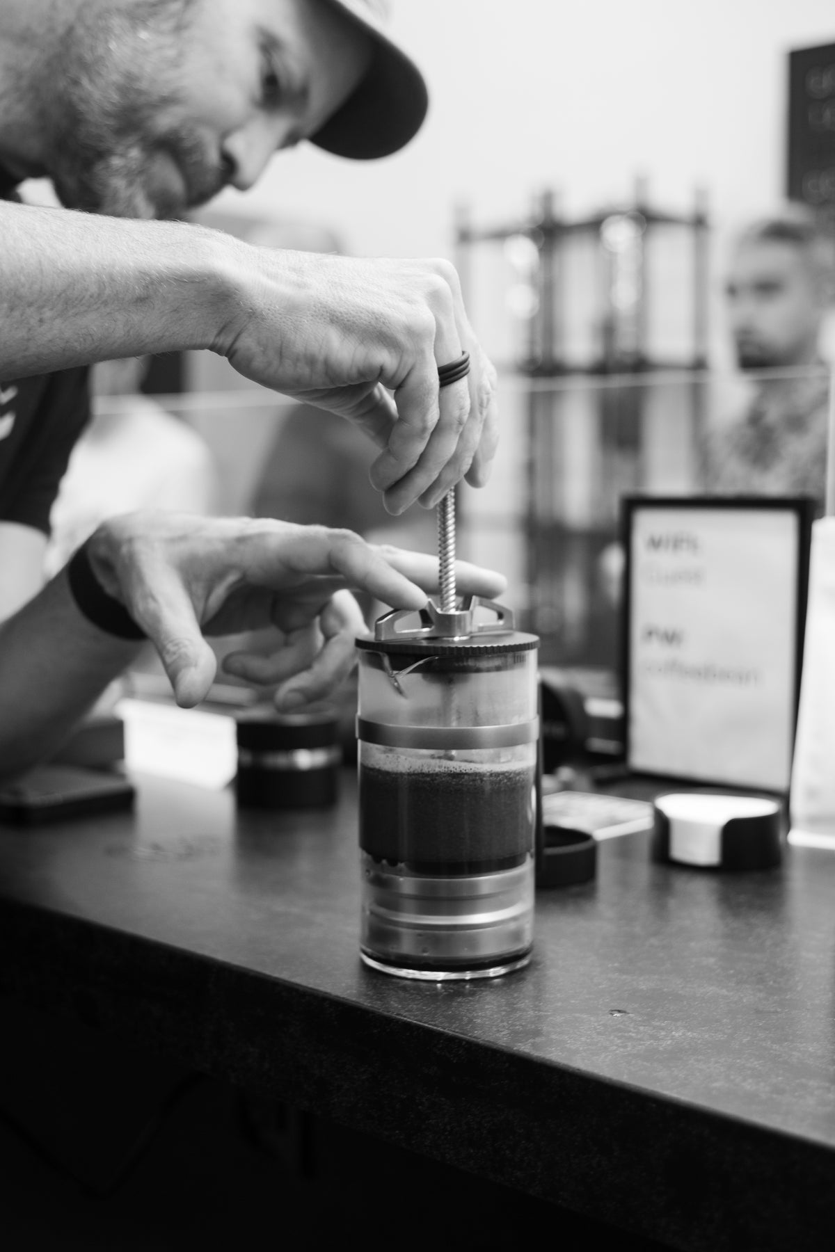 A hand stirring coffee in a glass immersion brewer
