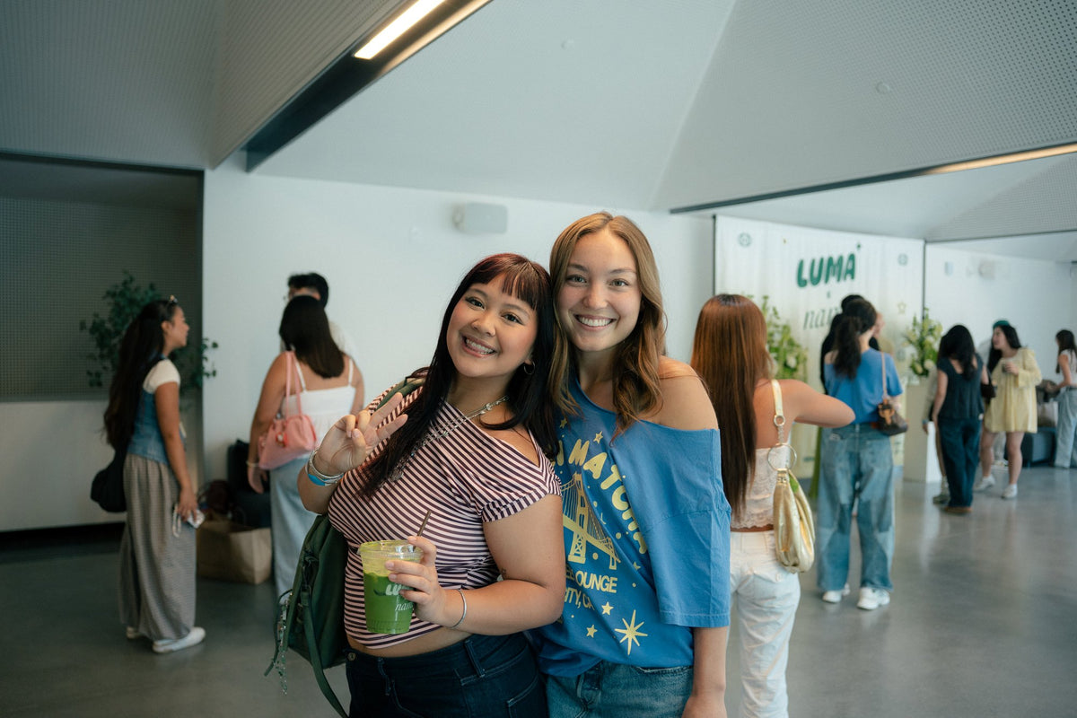 Two attendees smiling with matcha drinks inside Luma Coffee