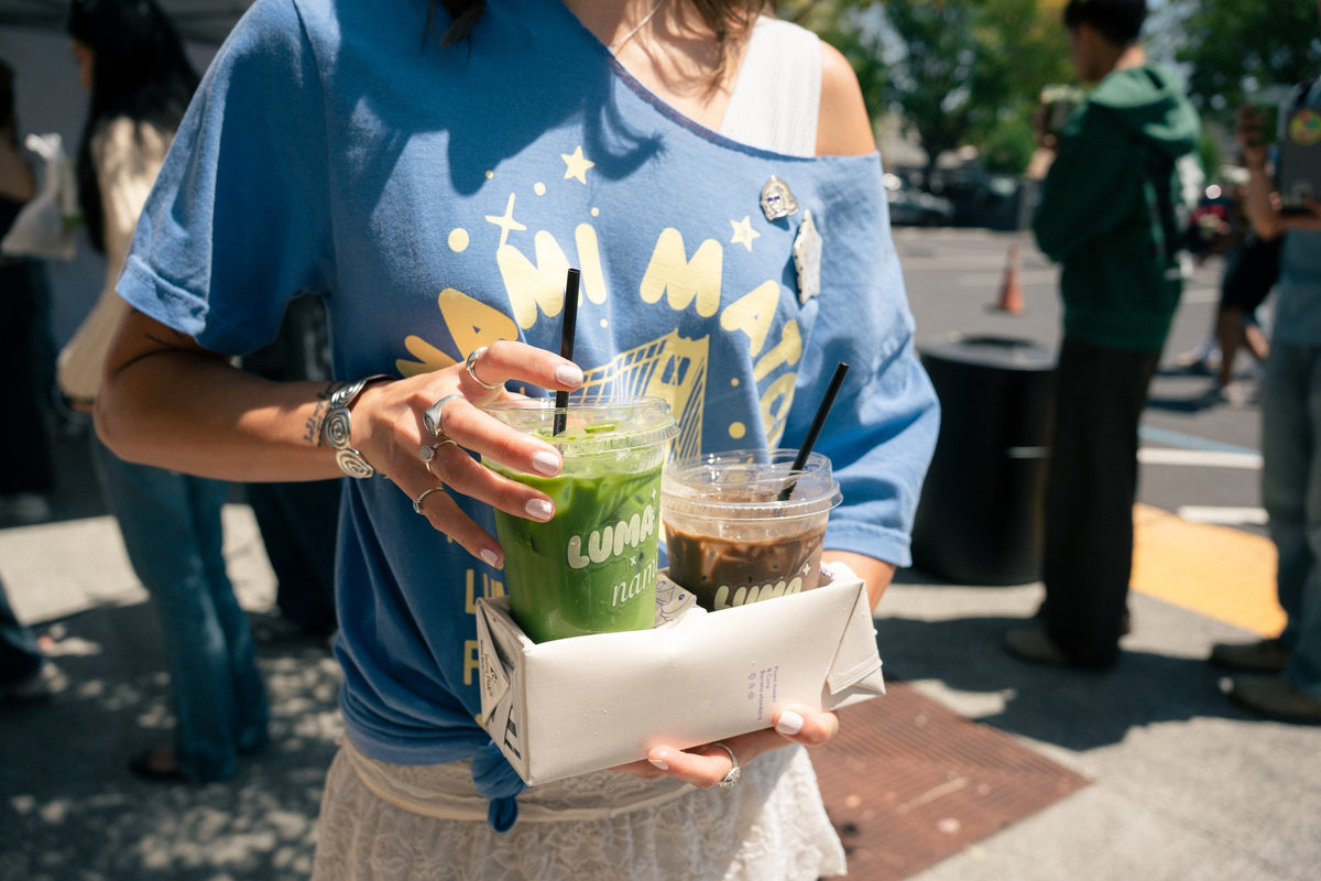 Event attendee carrying matcha and iced drinks outdoors