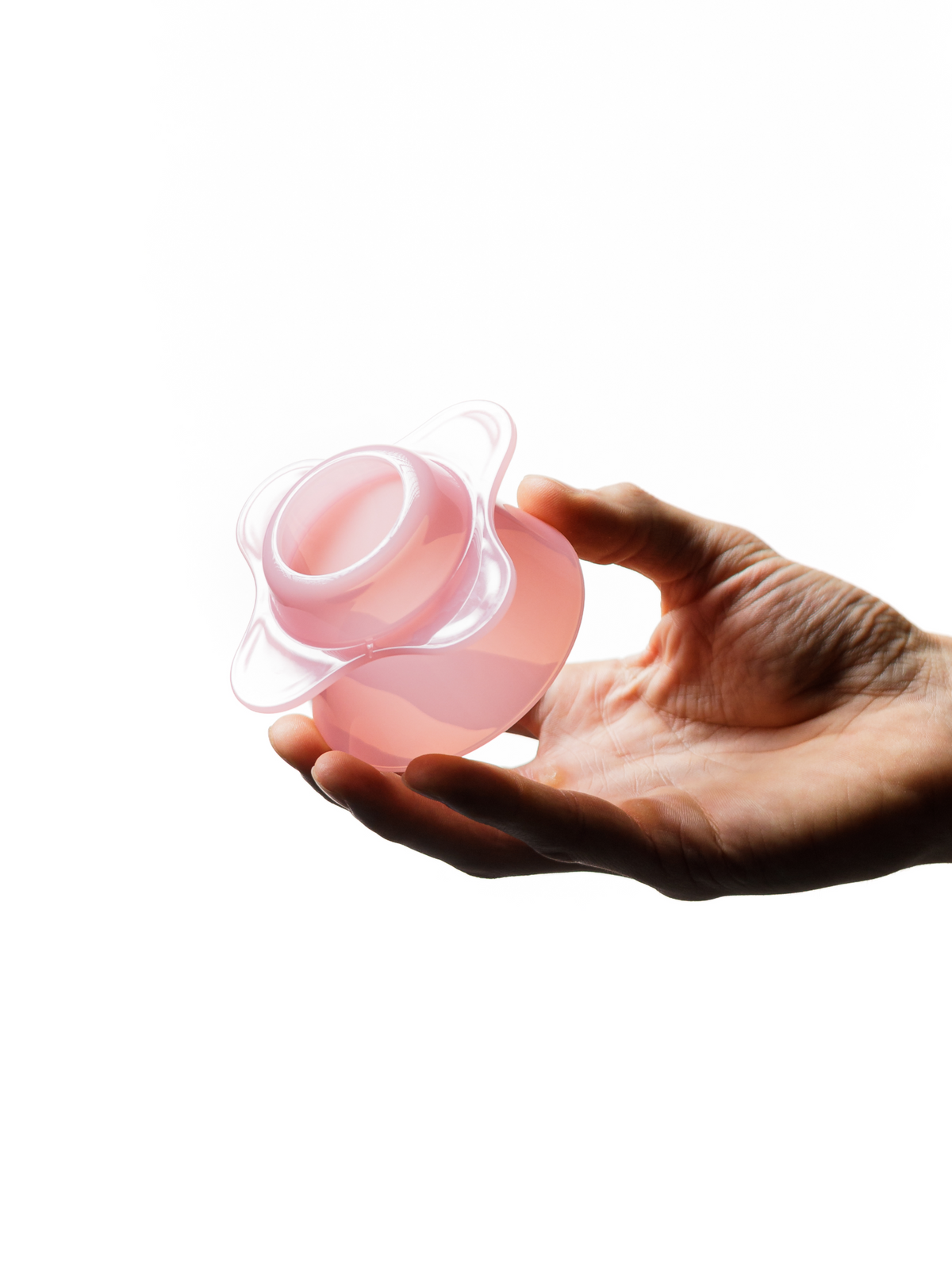 Vista de la base abierta del OREA O1 de plástico en Creamy Pink, sostenido con la mano